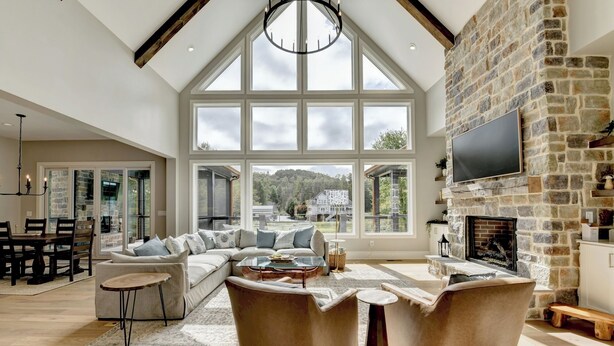 A spacious living room with a large stone fireplace, a comfortable sectional sofa, and a dining area with a table and chairs.
