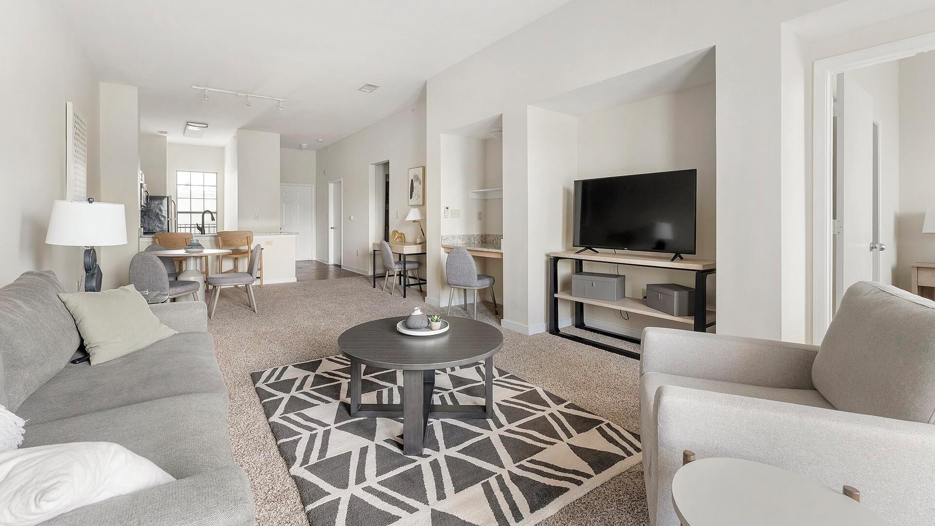 A modern living room with a sofa, armchairs, a coffee table, and a TV.