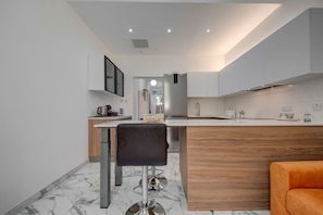 Una cocina moderna con piso de mármol, una isla de madera y una silla negra.