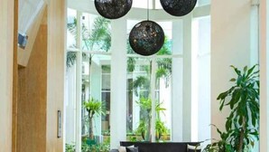 A modern interior with a sofa, pendant lights, and a view of greenery outside. - Fraser Residence Sudirman Jakarta (South Jakarta)
