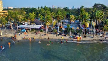 A beach with palm trees, umbrellas, and people.