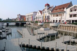 Une promenade le long de la rivière, bordée de bâtiments, avec un pont et des bateaux.