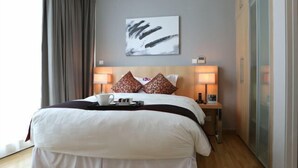 Een hotelkamer met een groot bed, twee bedlampen, een schilderij aan de muur en uitzicht op het omliggende landschap.