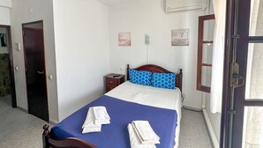 A bedroom with a bed, a nightstand, a wall-mounted air conditioner, and a door. - Residencial Boavistense by Umbral (Odemira)