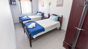 A room with two wooden beds, each with a blue and white bedspread, and a wooden wardrobe. - Residencial Boavistense by Umbral (Odemira)