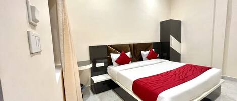 A hotel room with a large bed, a nightstand, a wall-mounted TV, and a bathroom door.
