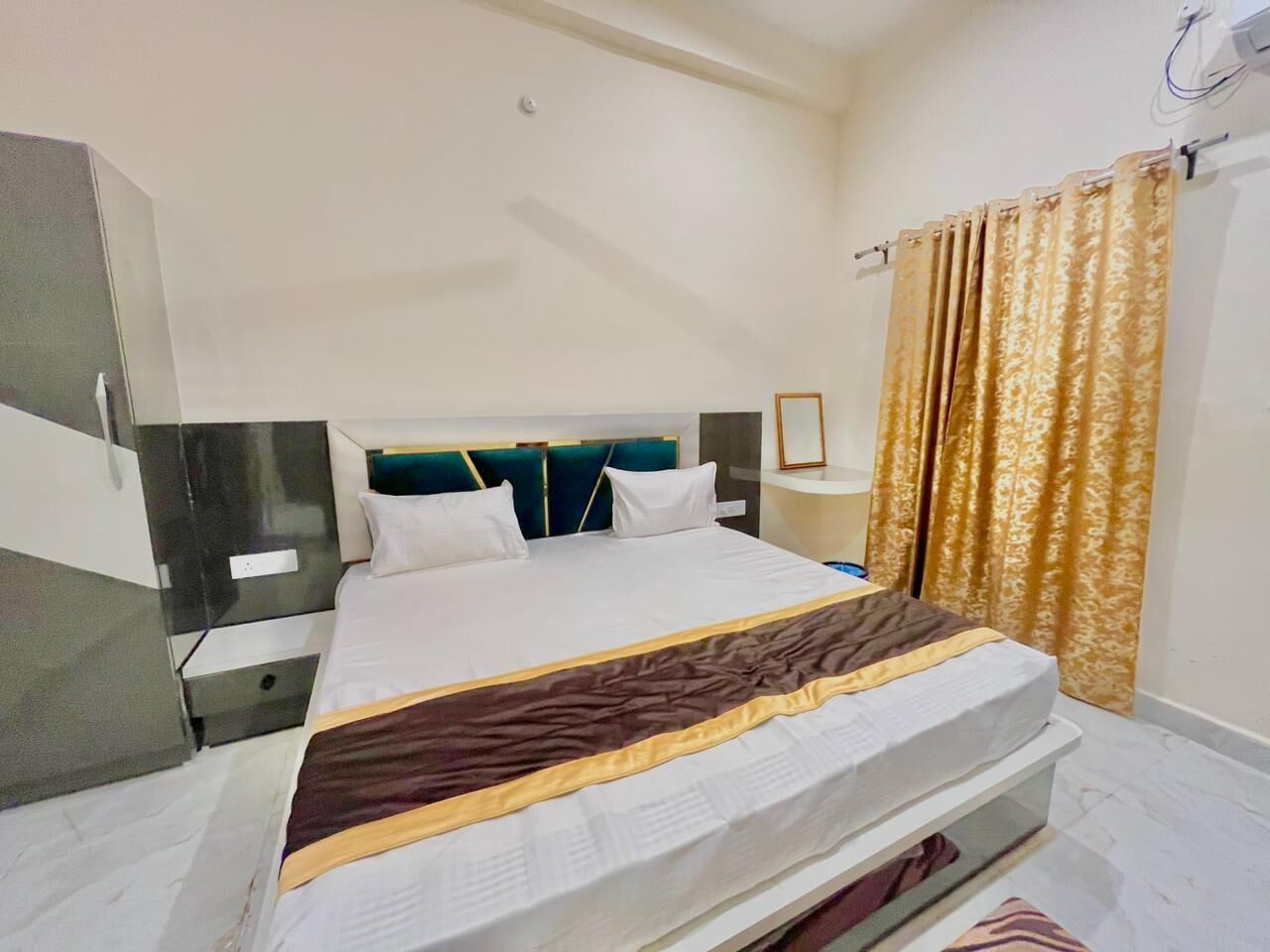 Una habitación de hotel con cama, mesitas de noche, armario y cortinas.
