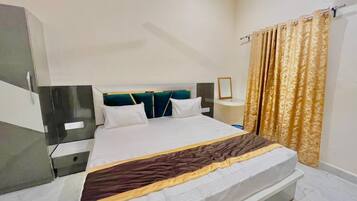 Una habitación de hotel con cama, mesitas de noche, armario y cortinas.
