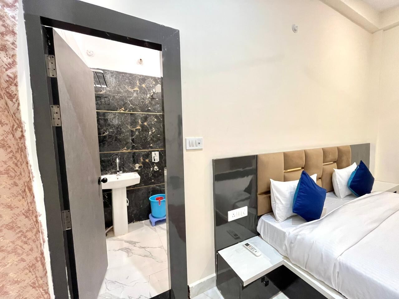 Ein modernes Hotelzimmer mit Bett, Nachttisch, Waschtisch und einem Badezimmer mit Waschbecken und Spiegel.
