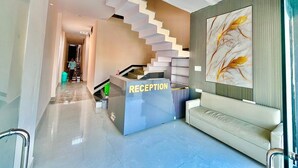 Un'area di accoglienza con una moderna scala, una reception e un divano.