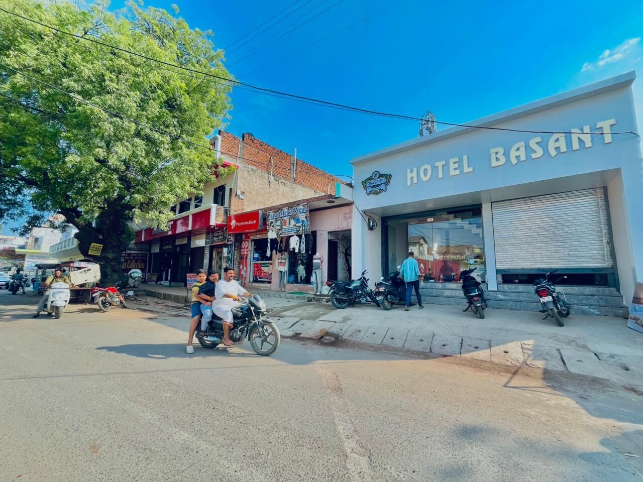 A street view with a building labeled "HOTEL BASANT" and a tree in the foreground.