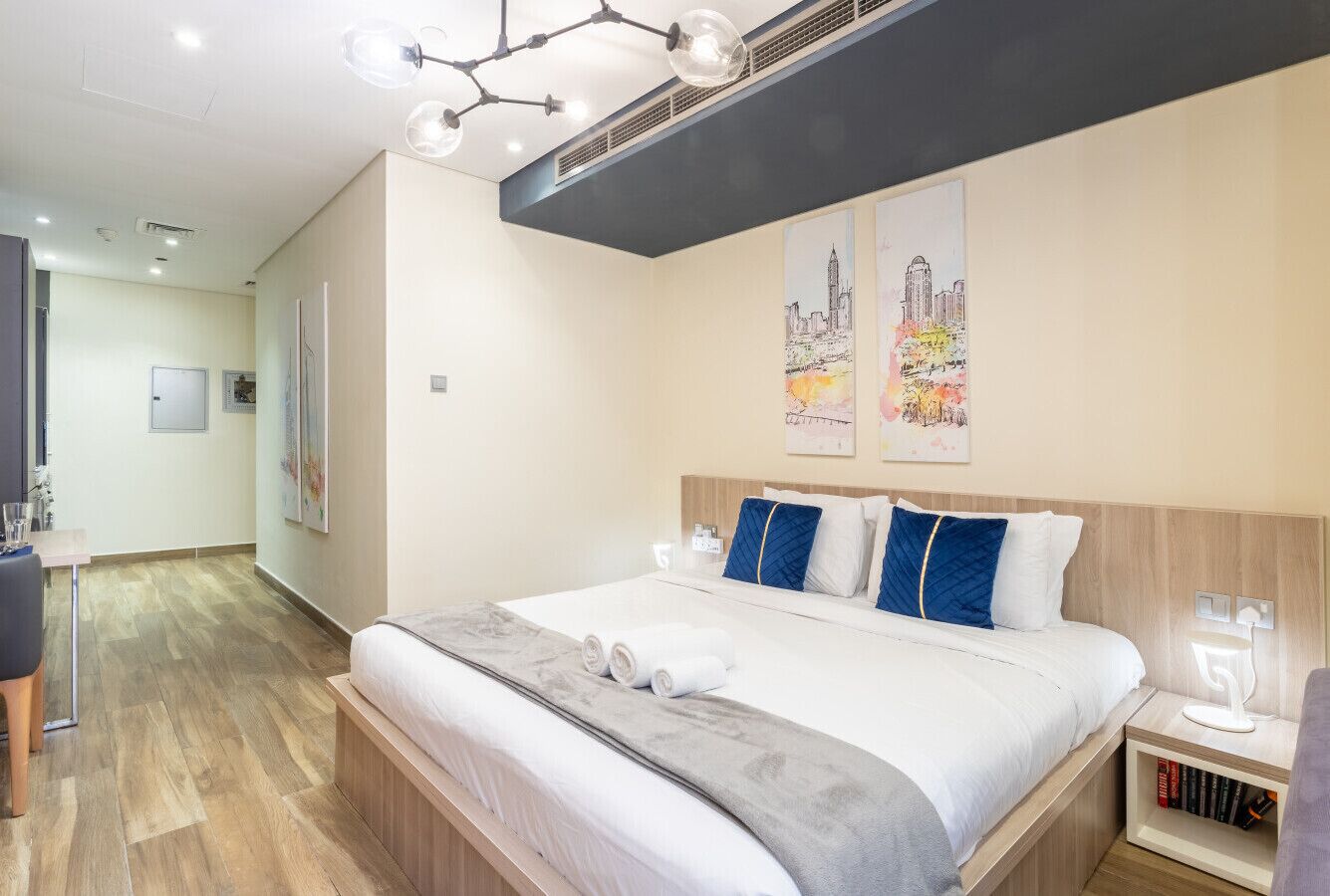 Ein Hotelzimmer mit einem großen Bett, einem Nachttisch mit Lampe und einer Wand-Klimaanlage.