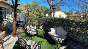 A patio with a table and chairs, a covered seating area, and a view of a garden and neighboring houses. - Charming Gardois Mazet in vacation residence (Gaujac)