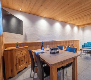 Un interior de madera con una mesa de comedor, sillas, un televisor montado en la pared y un letrero que dice 'LE RAMFOILLY'.