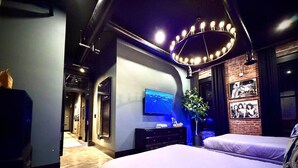 Un dormitorio moderno con una cama grande, un televisor, un aparador y una lámpara de techo original.