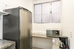 A kitchen with a stainless steel refrigerator, a microwave, and a coffee maker on the counter.
