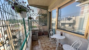 A balcony with a tiled floor, two white metal chairs, a small round table, and a potted plant. - Spazioso 3 Camere con Balcone AC Vaticano (Roma)