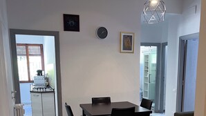 A dining area with a marble floor, a dining table with chairs, a hanging light fixture, and a clock on the wall. - Spazioso 3 Camere con Balcone AC Vaticano (Roma)