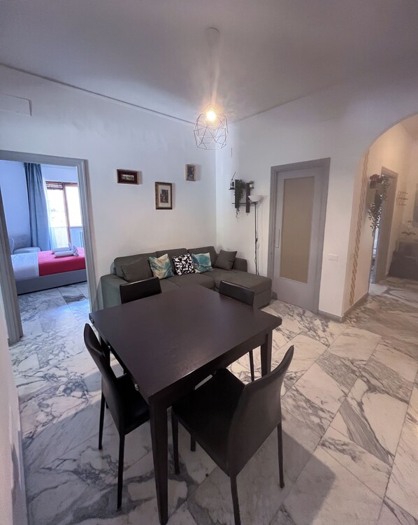 Un comedor con piso de mármol, una mesa de madera oscura y cuatro sillas.