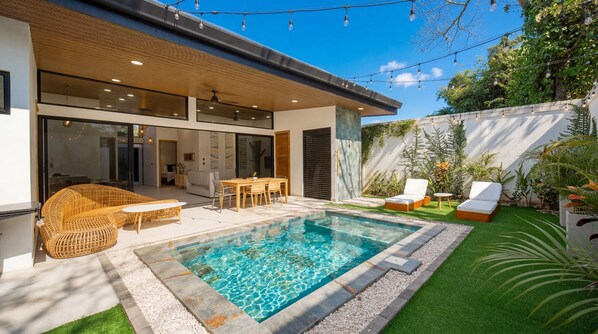 Une maison moderne dotĂ©e dâune piscine, dâun espace salon extĂ©rieur et dâun jardin.
