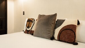Una cama con muchas almohadas, un interruptor de pared y una puerta.