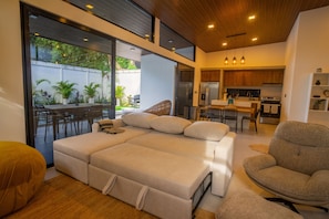 A modern living room with a sofa, a dining area, and a kitchen.
