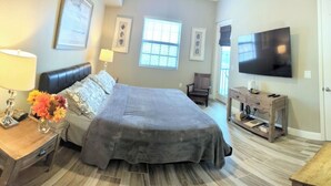 Quarto com cama, mesas de cabeceira, televisão e janela.