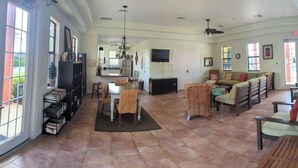Uma sala de estar ampla com uma mesa de jantar, cadeiras, sofá e televisão.