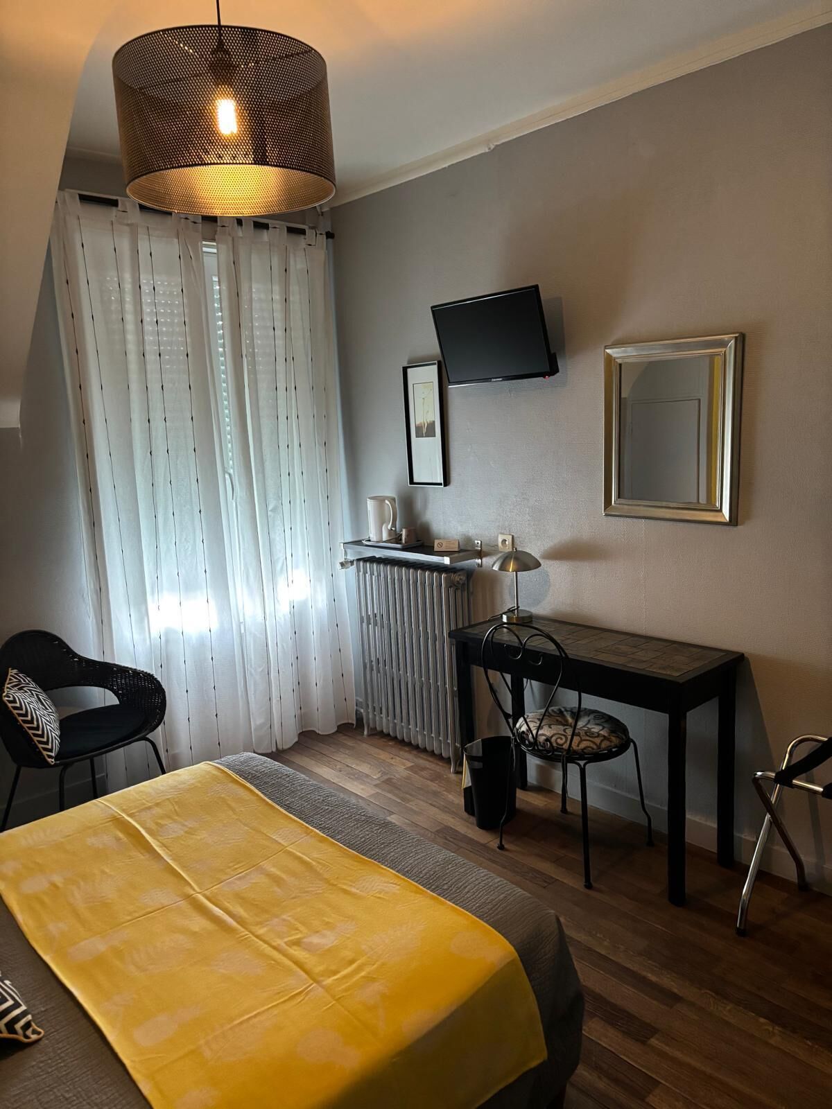 Ein Hotelzimmer mit einem Bett, einem Schreibtisch, einem Stuhl, einem Fernseher und einer Heizung.