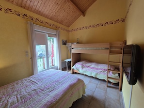 A room with two bunk beds, a wooden ceiling, and a window with a view of a red fence and greenery outside. - Gite 15 mn from Beauval zoo (Meusnes)