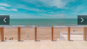 A beach view with a wooden fence and a clear sky.