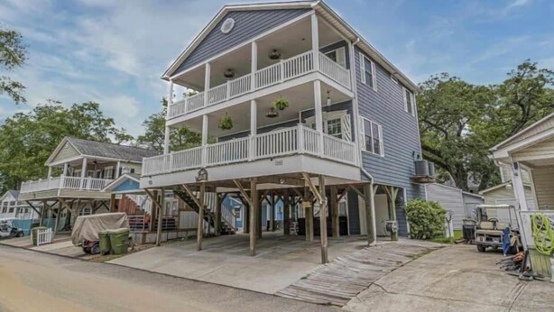 A two-story house with a balcony on the first floor and a covered porch area.