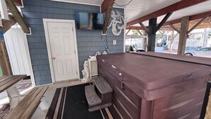 A pool table in a covered area with a door and a mounted TV.