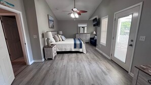 A bedroom with a bed, nightstands, a dresser, a ceiling fan, and a TV.