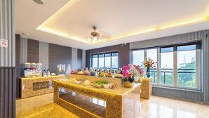 A modern hotel lobby with a marble reception desk, large windows with a city view, and a ceiling fan. - Xaysomboun Hotel  (Vientiane)