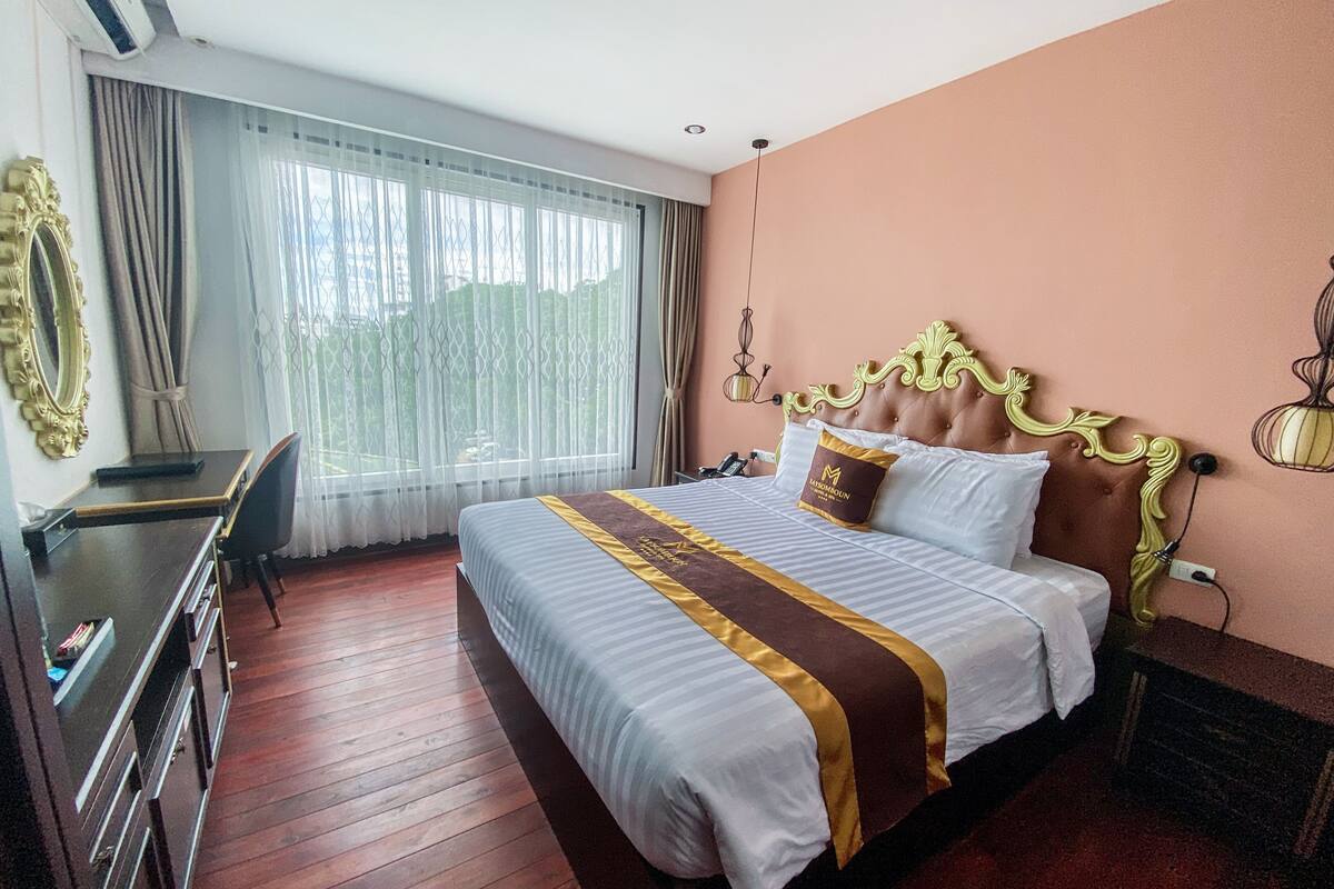 A hotel room with a large bed, a desk, and a chair.