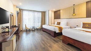 A hotel room with two beds, a desk, a TV, and a large window with curtains. - Xaysomboun Hotel  (Vientiane)
