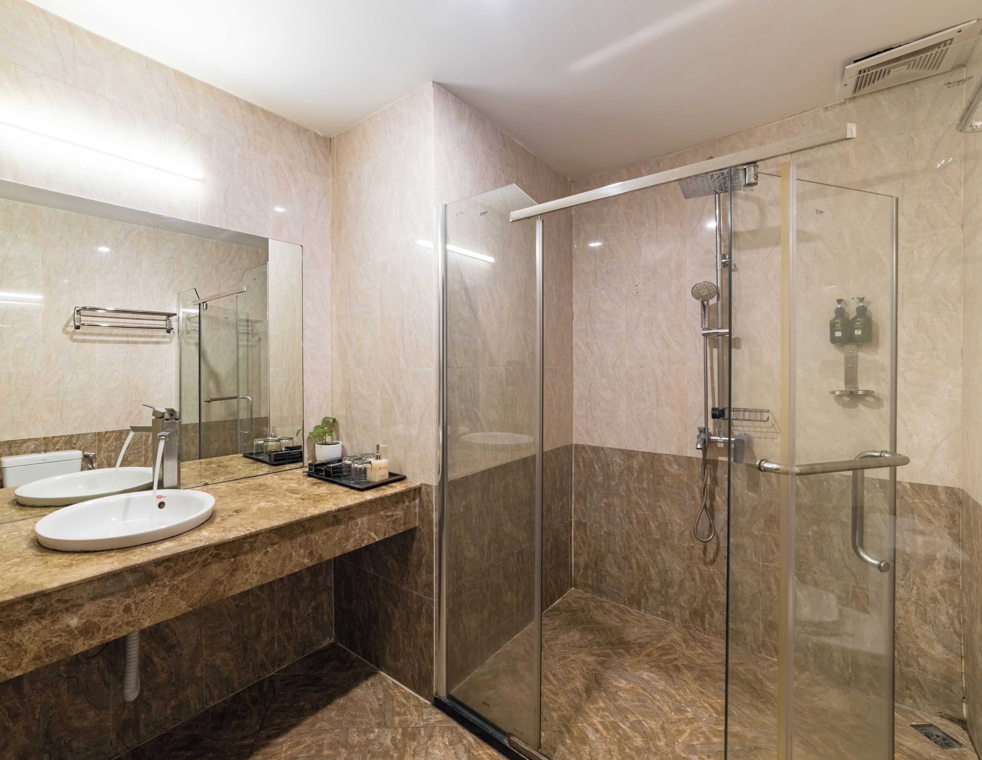 Un baño moderno con ducha de vidrio, lavamanos con espejo y un perchero para toallas.