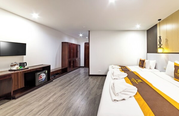 Une chambre d’hôtel moderne dotée d’un grand lit, d’une télévision à écran plat, d’un minibar et d’une armoire en bois.