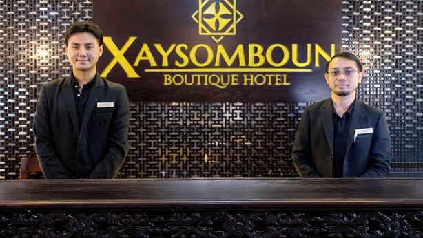 Two individuals standing in front of a wall with a logo and text reading "Xaysomboun Boutique Hotel". - Xaysomboun Hotel  (Vientiane)