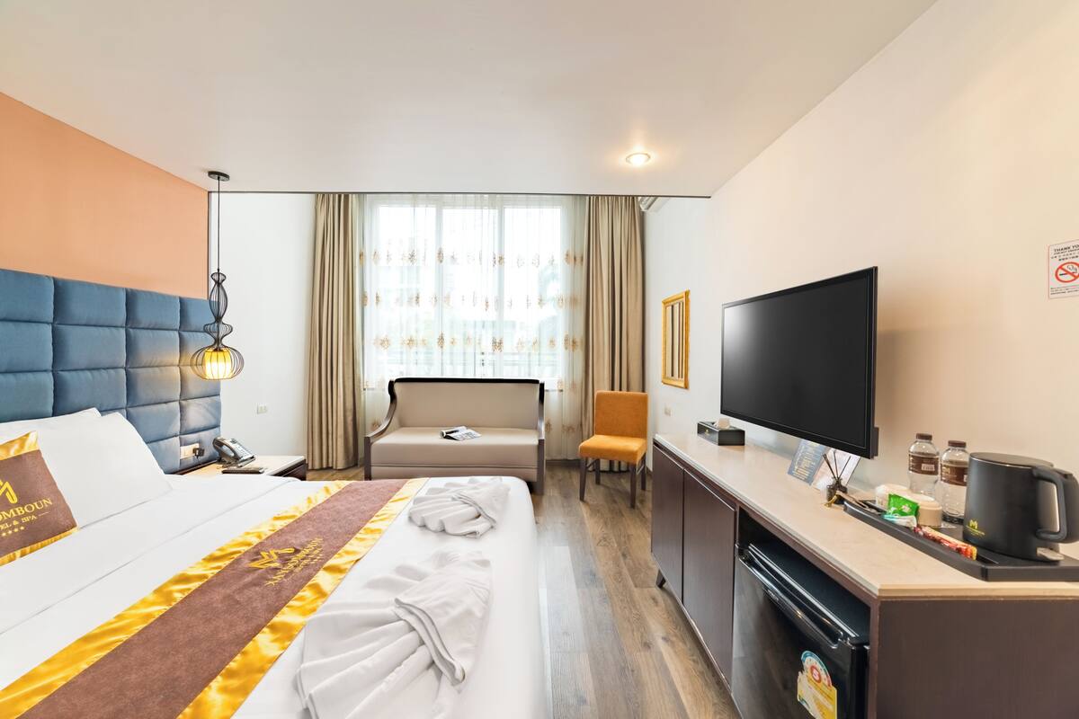 A hotel room with a bed, a desk, a television, and a minibar.