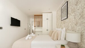 Un dormitorio moderno con cama, mesita de noche, lámpara y armario.