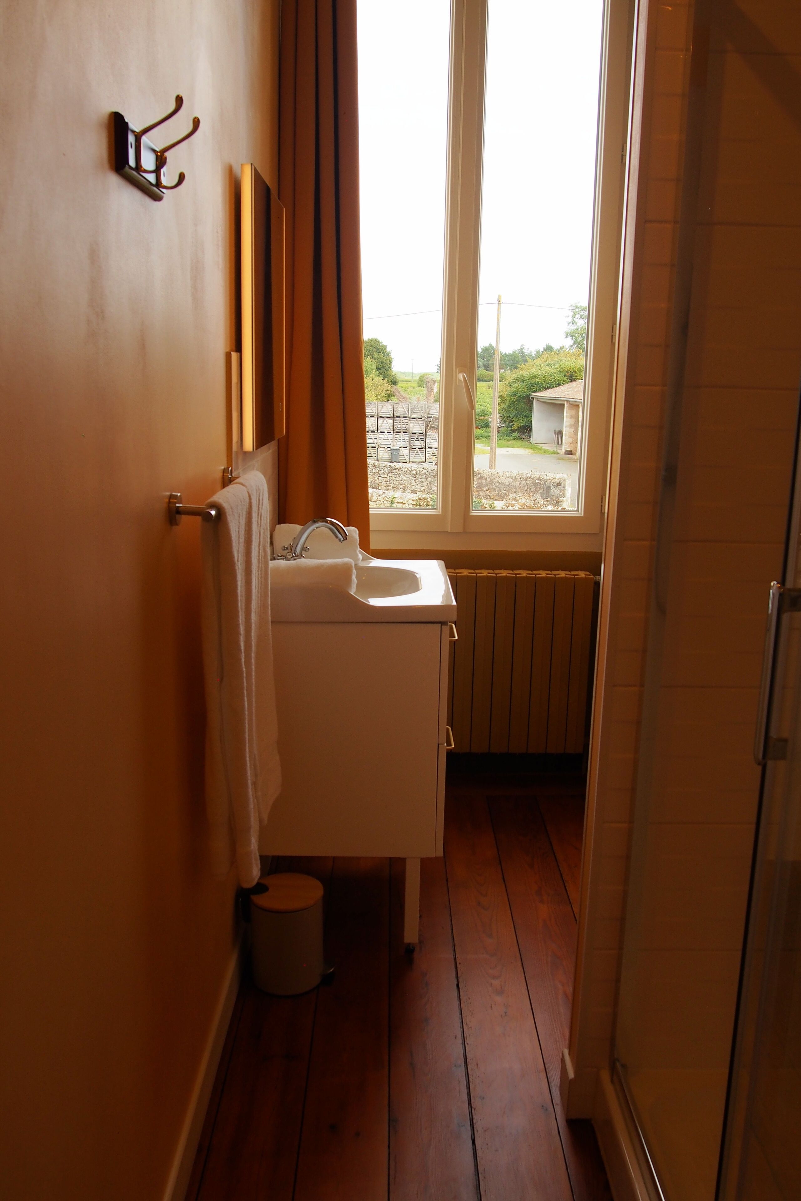 Un baño con ventana, lavamanos y perchero.