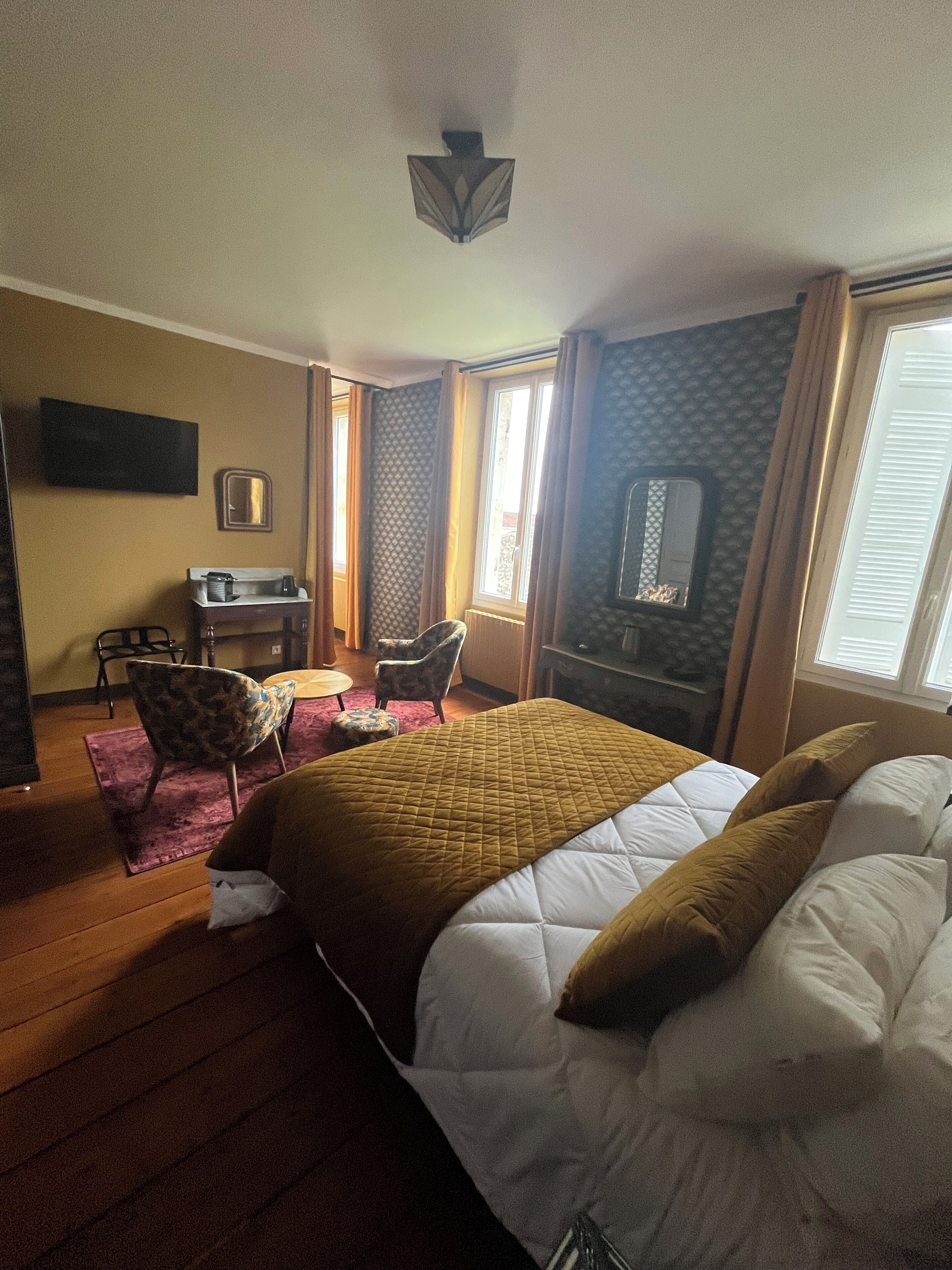 A hotel room with a bed, a desk, a chair, and a television.