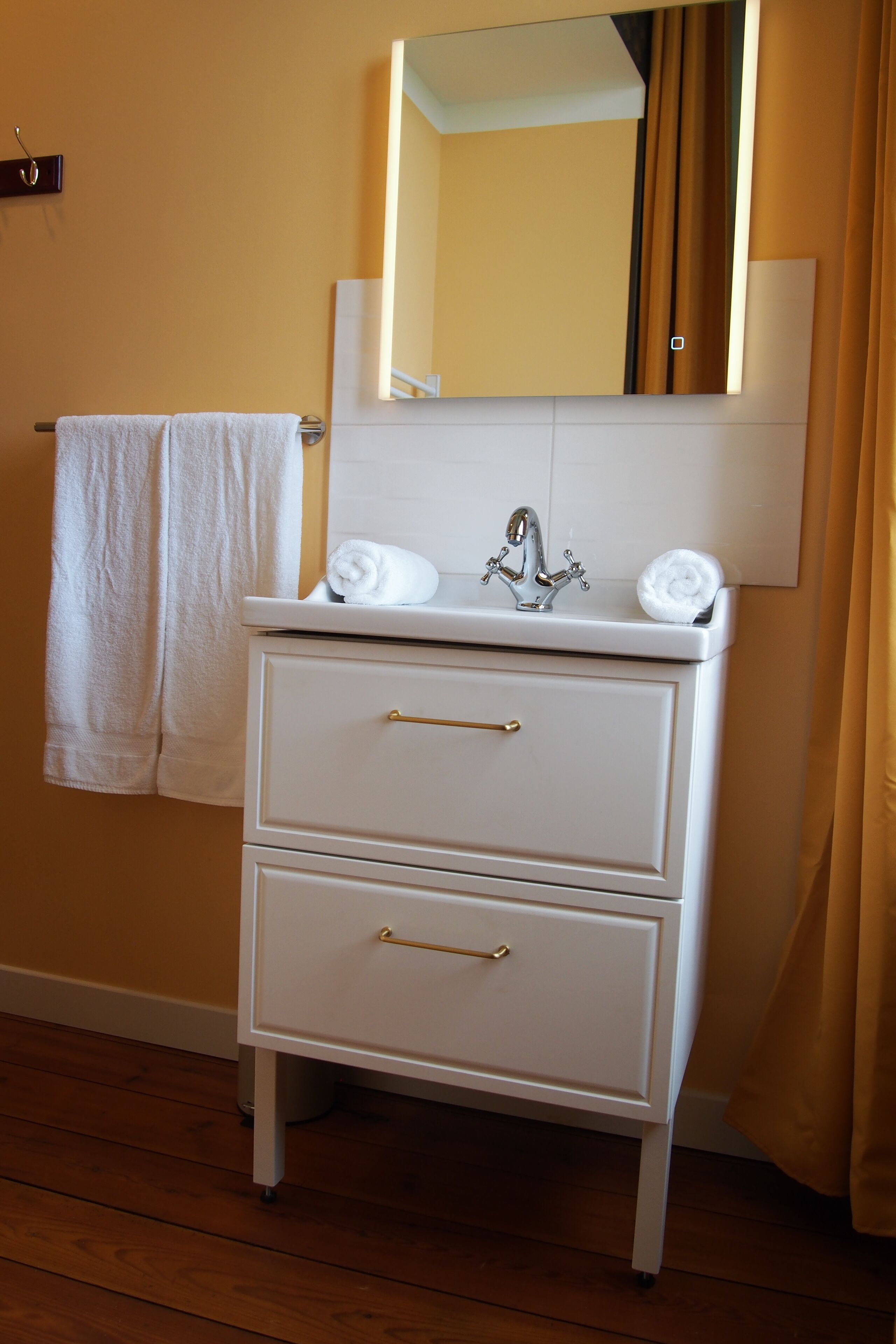 A bathroom with a white vanity, a mirror, and two towels.