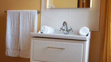 A bathroom with a white vanity, a mirror, and two towels.