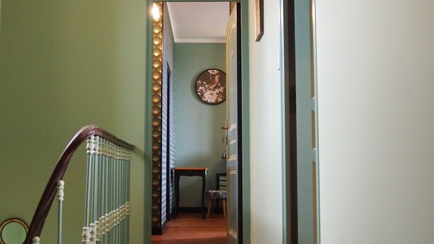A hallway with a wooden floor, a radiator, and a hanging light fixture.