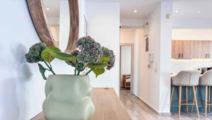 Ein modernes Interieur mit einem Holztisch, einer grünen Vase mit Pflanzen und einer Küche im Hintergrund.