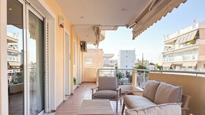 Ein Balkon mit einer Sitzecke, inklusive Sofa, Stühlen und Tisch, mit Blick auf eine Wohngegend.