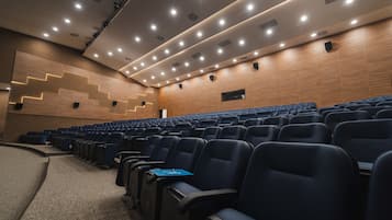Un teatro con filas de asientos, una pared de madera y luces en el techo.